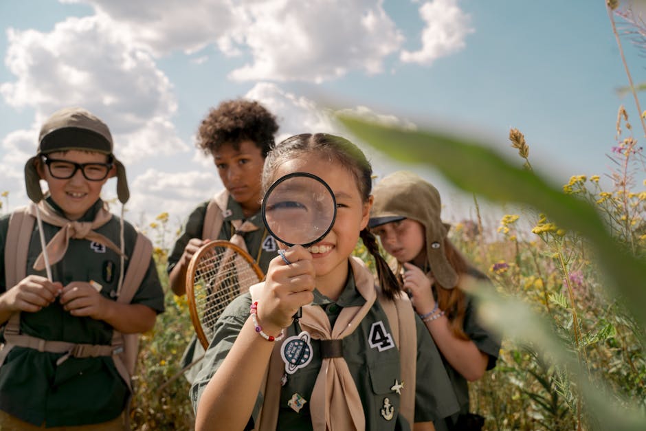 Bambini esploratori con lente d'ingrandimento durante gita scolastica scientifica alla scoperta dell'universo e della natura circostante.
