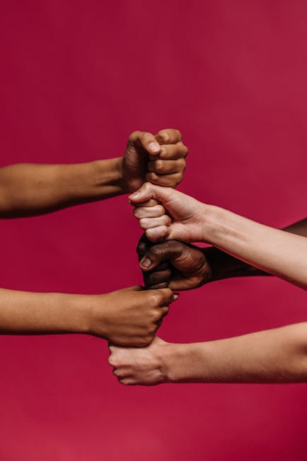 Mani di diverse etnie unite a pugno, simbolo di inclusione sociale e collaborazione per progetti di comunità e pari opportunità.