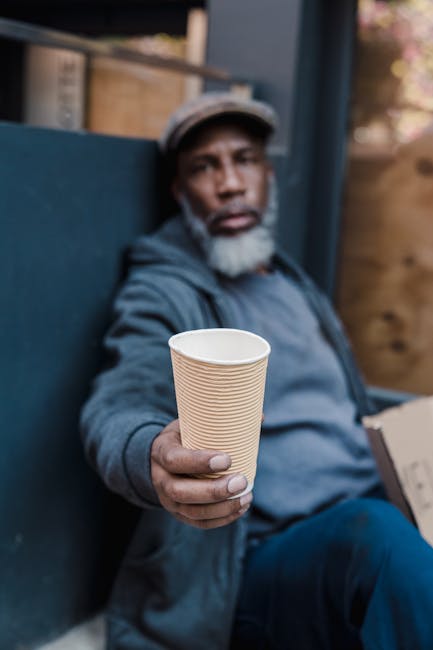 Uomo senzatetto con tazza in mano chiede aiuto. Impara a chiedere aiuto in francese per situazioni di emergenza e necessità.