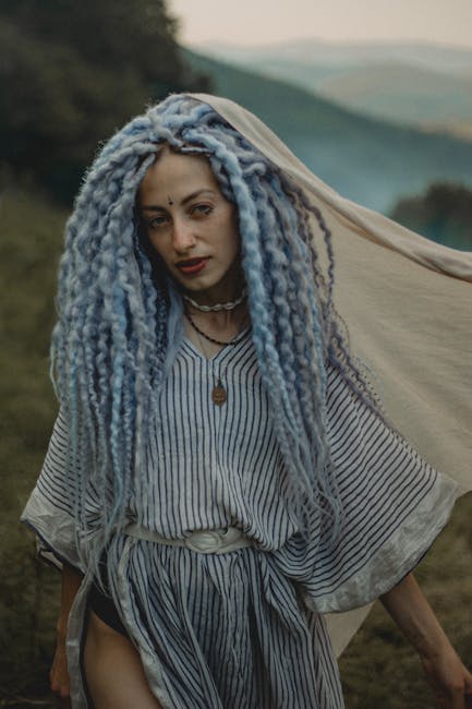 Ritratto di donna con dreadlocks azzurri e abito a righe, espressione poetica e connessione con la natura circostante
