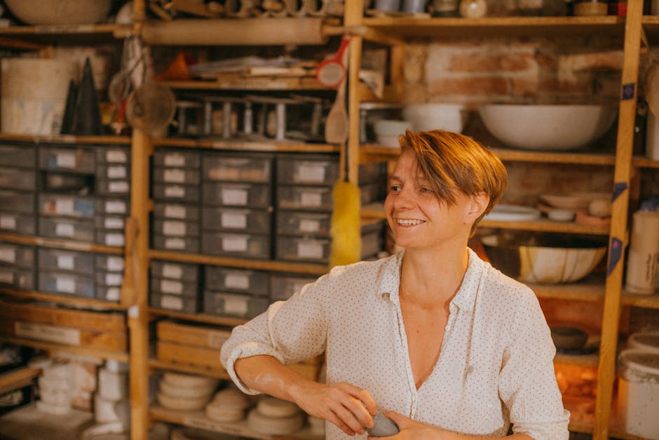Donna sorridente in studio di ceramica, espressione della scoperta della propria tecnica vocale unica e originale.