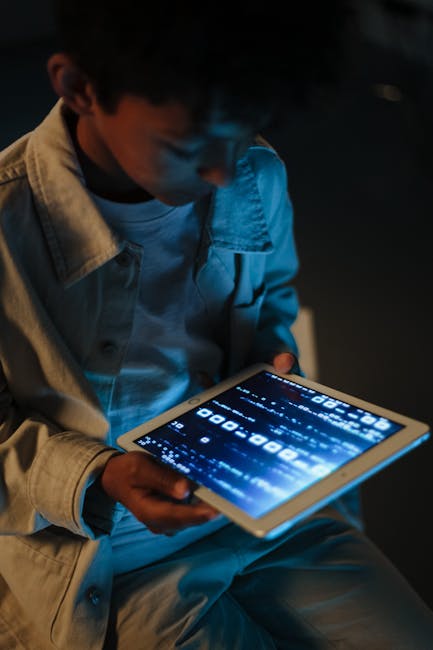 Ragazzo che utilizza un tablet con schermo luminoso, esempio di media literacy e apprendimento digitale per cittadini informati.