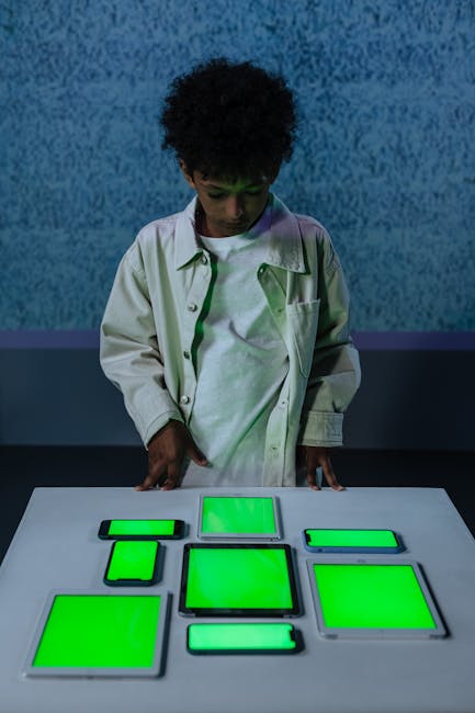 Bambino che interagisce con tablet e smartphone con schermi verdi, giochi musicali innovativi per apprendimento interattivo.