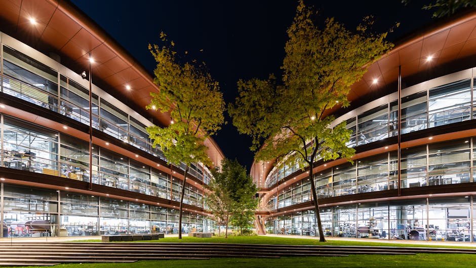 Edificio scolastico moderno illuminato di notte, riflesso del lavoro di squadra per il Contratto Collettivo Integrativo di Istituto.