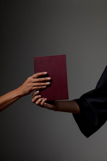 Consegna di un libro bordeaux, simbolo della guida dell'Università della Calabria e del futuro Rettore Gianluigi Greco esperto di IA.