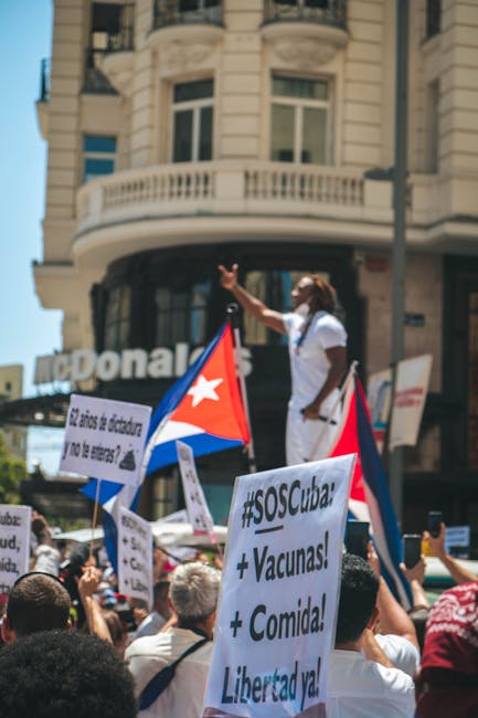 Manifestazione pro Cuba a Madrid per la Giornata della Solidarietà Umana con bandiere e cartelli che chiedono libertà e aiuti.