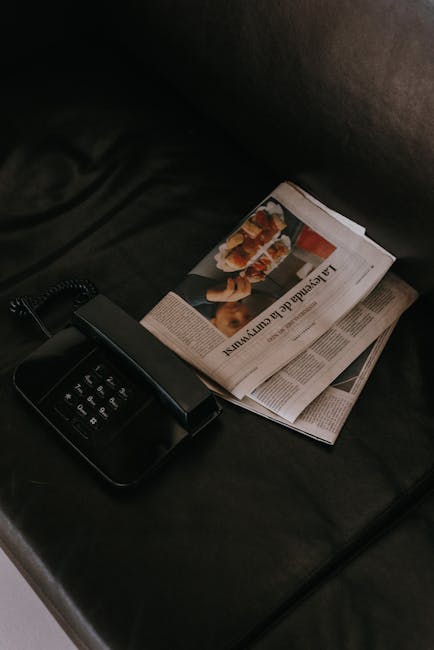 Telefono nero vintage accanto a giornali con articoli sull'amicizia e legami speciali, su sfondo scuro e riflessivo.