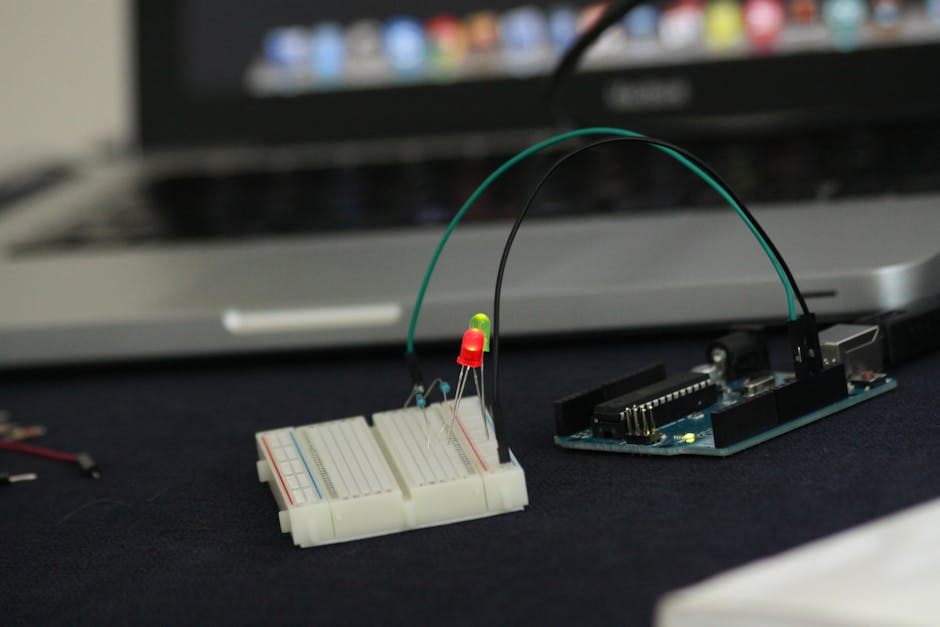 Prototipazione elettronica con Arduino e breadboard per coding e digital makers, LED accesi e laptop sullo sfondo.