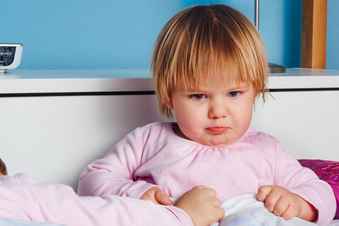 Bambina turbata in pigiama rosa, possibile reazione a tentativo di prelievo non autorizzato all'asilo, esprime preoccupazione e disagio