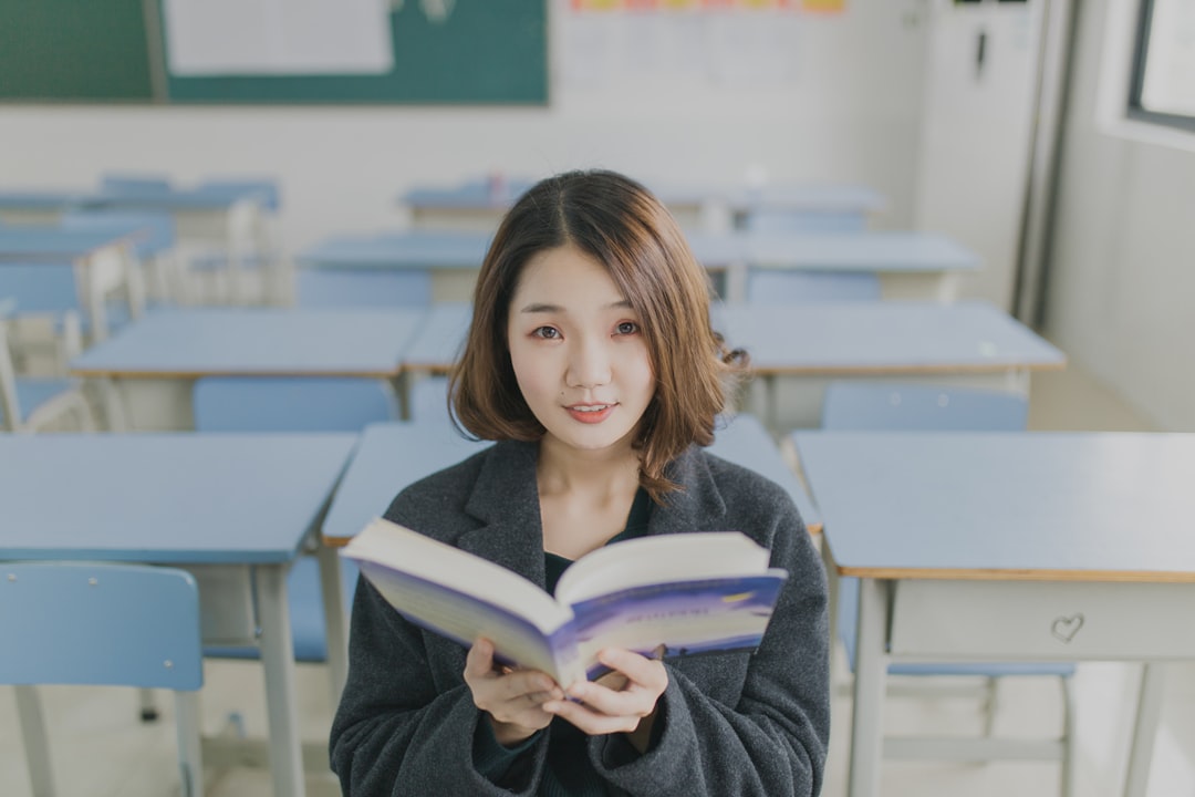Studentessa legge libro in aula scolastica vuota. Valutazione studenti secondo ciclo istruzione. Focus su apprendimento e didattica efficace.