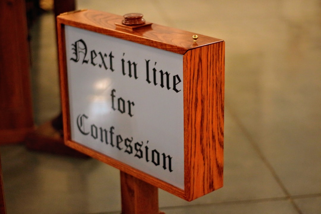 Segnale in legno con scritta Next in line for Confession, indicazione per la confessione in chiesa, attesa e riflessione.