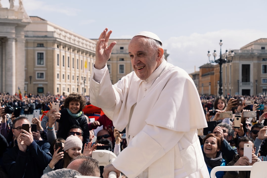 Papa Francesco saluta la folla durante un evento pubblico, con molti fedeli che scattano foto con i loro smartphone, in un contesto legato alla Maturità 2026.