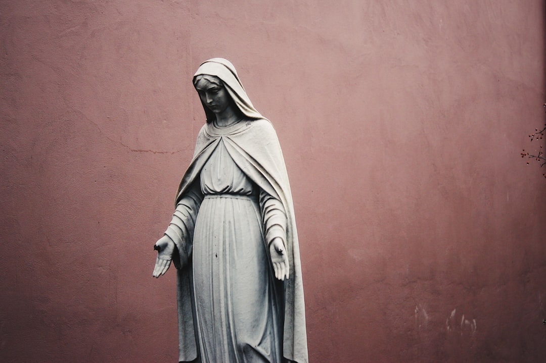 Statua della Madonna con mani aperte, simbolo di accettazione e resilienza di fronte a scelte professionali limitate.