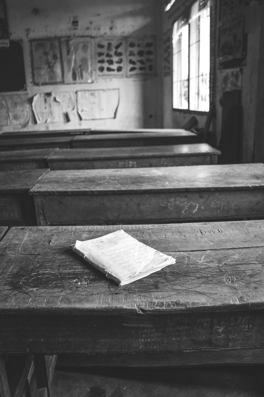 Aula scolastica vuota con banchi in legno e quaderno, immagine evocativa della responsabilità scolastica e della sicurezza degli alunni.