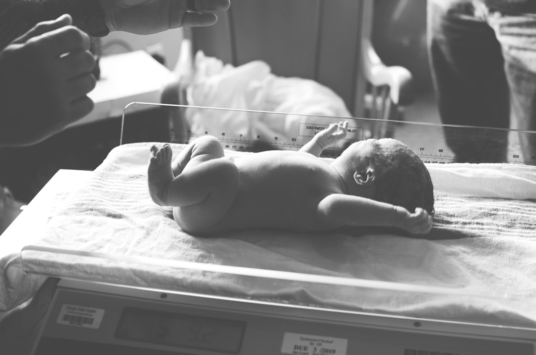 Neonato disteso sulla bilancia in ospedale, immagine in bianco e nero per articolo su bonus nuovi nati e agevolazioni INPS 2026.