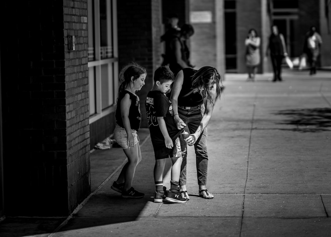 Madre che sistema i vestiti del figlio in strada: metafora della protezione e attenzione contro il bullismo e la sottovalutazione adulta.