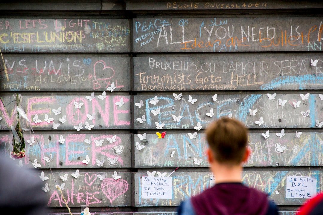 Muro con scritte di solidarietà e farfalle bianche, simbolo di resilienza e speranza, in memoria delle vittime di attentati, un invito alla pace.