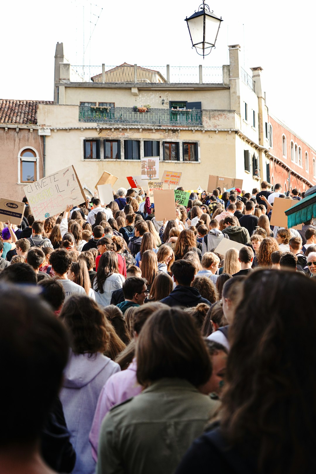Manifestazione studentesca contro la violenza politica a Sant’Agata Li Battiati, ispirata dall'incontro con Giuseppe Culicchia. Giovani con cartelli.