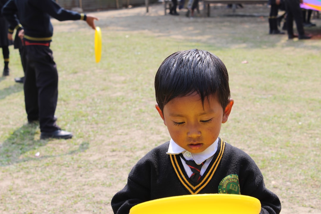 Bambino gioca con frisbee giallo all'aperto, esempio di apprendimento esperienziale nella scuola primaria, promuovendo scoperta e sperimentazione.