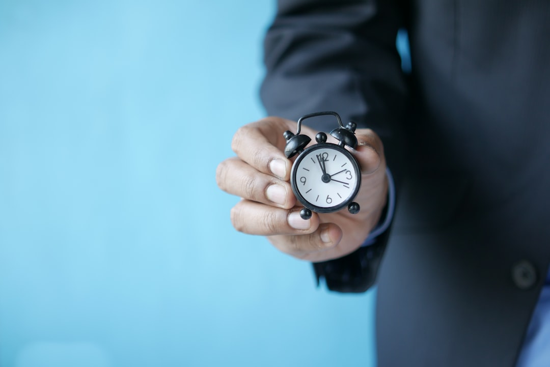 Uomo in giacca tiene in mano una sveglia, simbolo dell'eccesso di ore di lavoro straordinario e del diritto al risarcimento per il lavoratore.