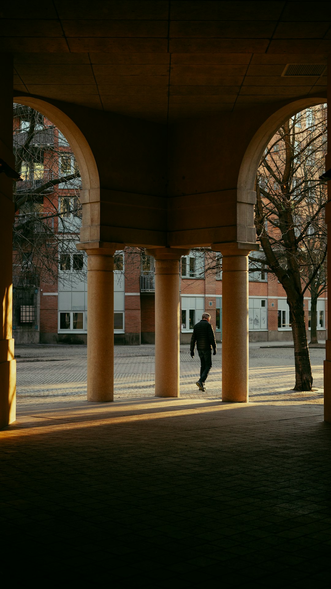 Uomo che cammina sotto portici universitari, simbolo di dialogo e movimento verso la conoscenza, in linea con il pensiero di Bernini.