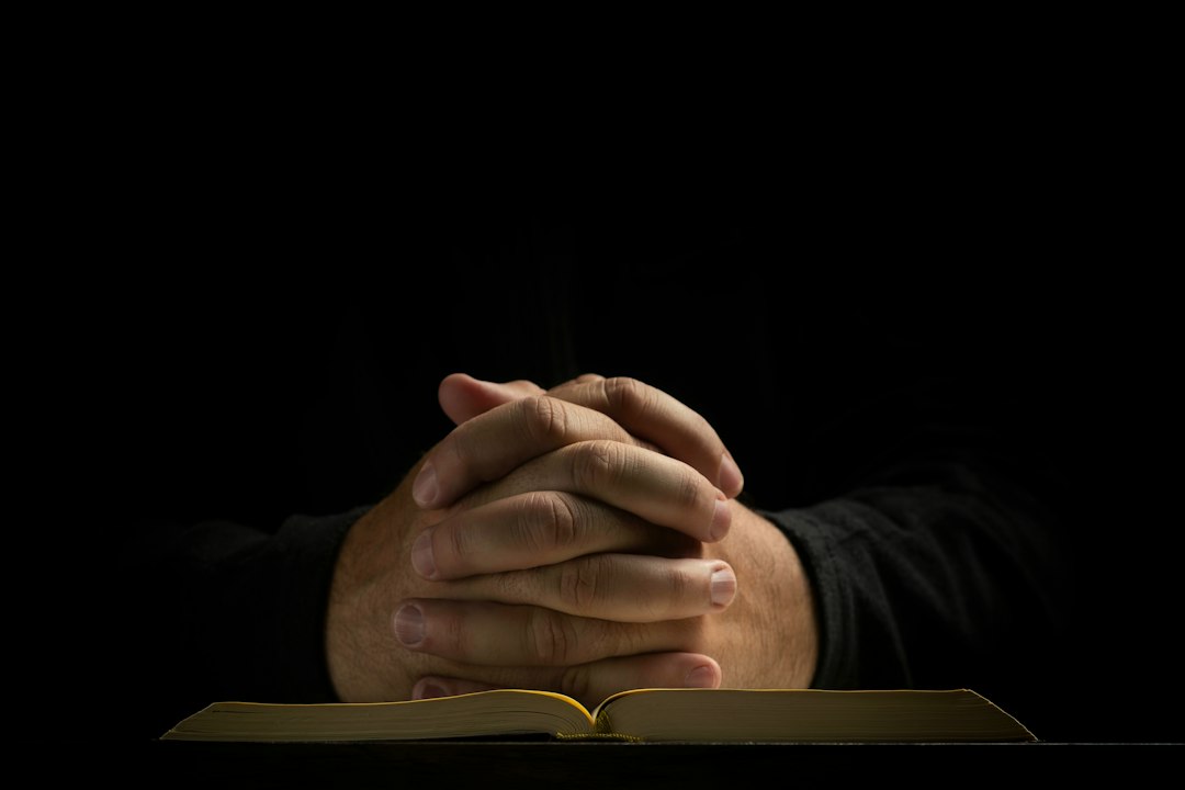 Mani giunte su un libro aperto, simbolo della preghiera e della riflessione dei docenti di religione in attesa del superamento del tetto del 70% per l'organico di ruolo.