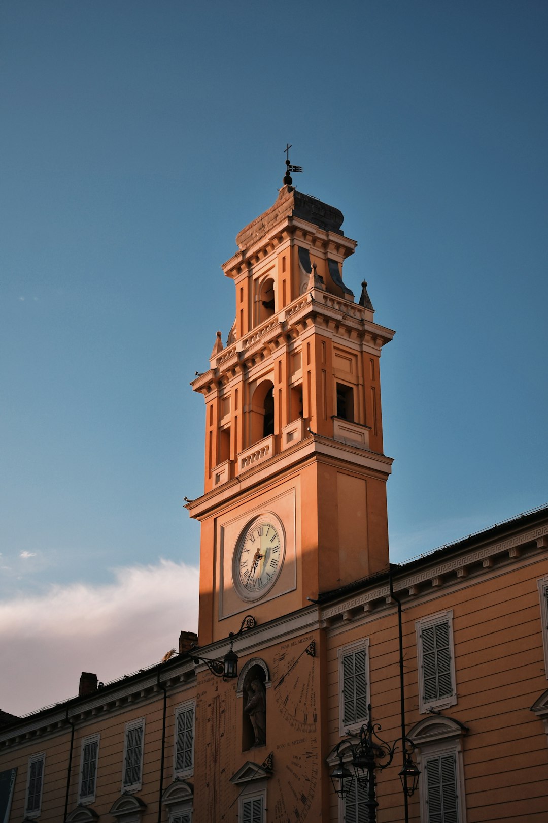 Torre civica di Parma con orologio e meridiana, simbolo di autorevolezza e legalità nel contesto scolastico secondo Valditara.