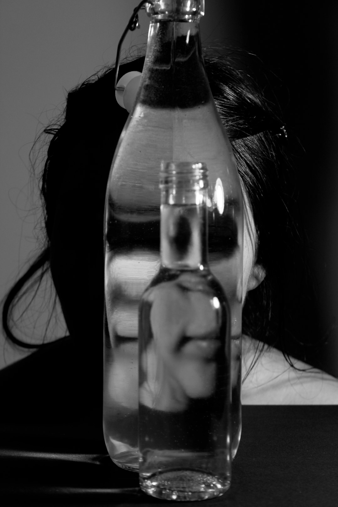 Ragazza riflessa in bottiglie d'acqua, metafora del coma etilico e dei rischi dell'alcol a scuola, gita scolastica e vodka nella borraccia