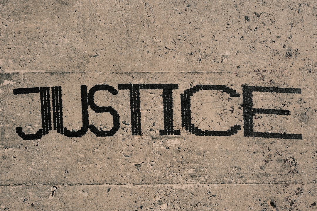 La parola JUSTICE incisa su cemento grezzo, simbolo del sistema giudiziario e delle sue implicazioni
