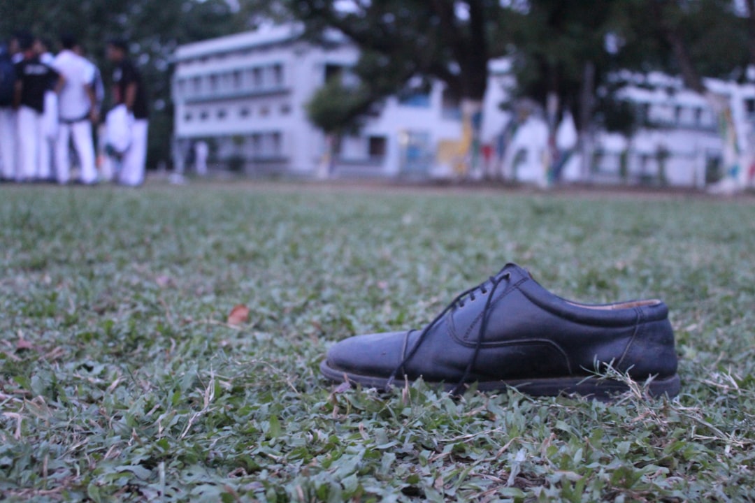 Scarpa nera abbandonata sul prato scolastico, simbolo di un infortunio o negligenza. Riflessioni sulla sicurezza e responsabilità della scuola.