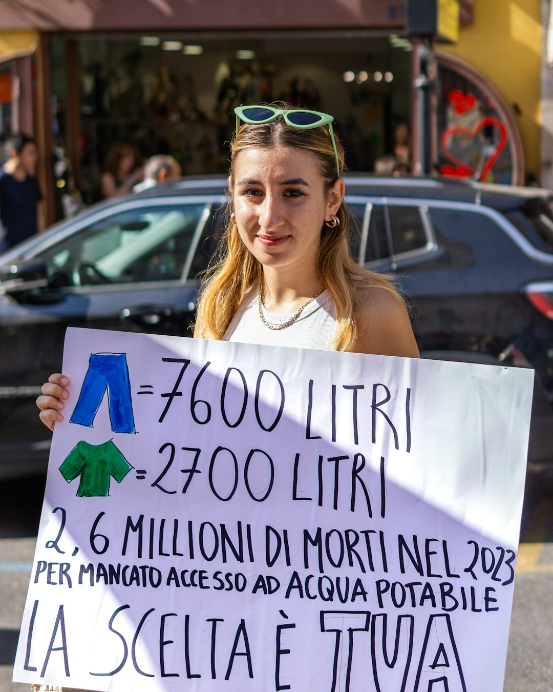 Ragazza con cartello sull'impatto idrico dell'abbigliamento e la crisi idrica globale, sensibilizzazione e scelte sostenibili