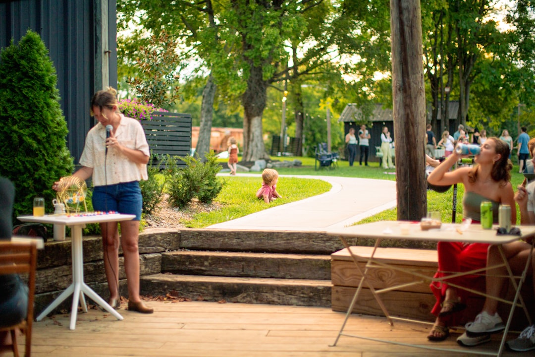 Scuola all'aperto: insegnante con microfono e tombola, bambini e adulti in un parco verde. Un modello innovativo di didattica.