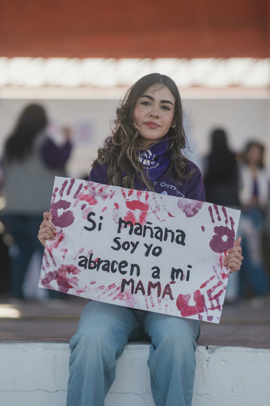 Donna manifesta contro la violenza scolastica con cartello Si mañana soy yo abracen a mi mama, simbolo di prevenzione e sicurezza