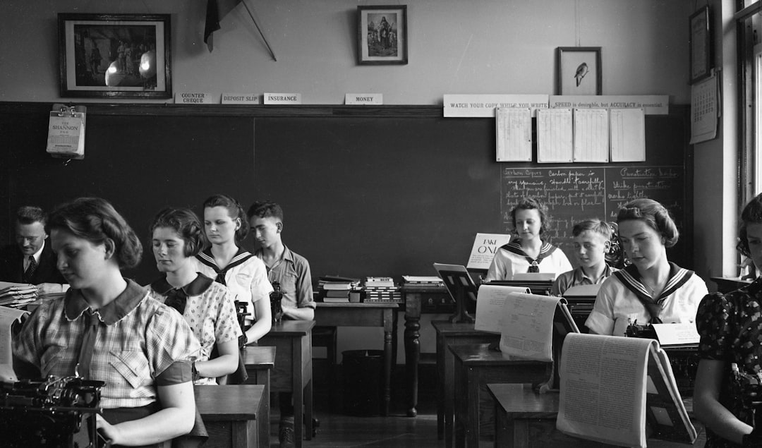 Foto d'epoca di studenti in classe di dattilografia, riflessione sui viaggi scolastici e i rischi legati all'alcol tra i giovani.